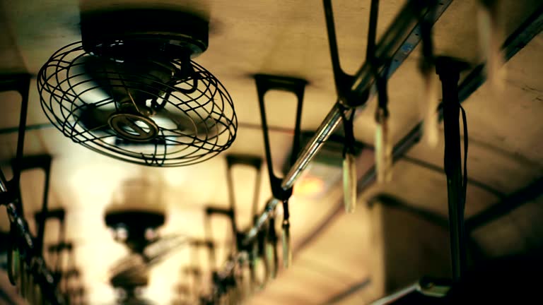 Interior of the old train with ceiling fan and handrails in passenger carriage.