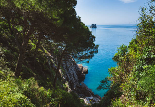 Hidden bay and lonely Sveta Nedjelja island view on the coast path to Petrovac, Montenegro. Rocks and seaview on the way from Perazica Do to Petrovac.