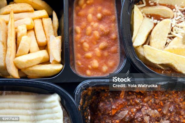 Microwaveable Ready To Eat Meals Of Chips Mince Beans Lasagna In Black Plastic Boxes Still Unfrozen Stock Photo - Download Image Now