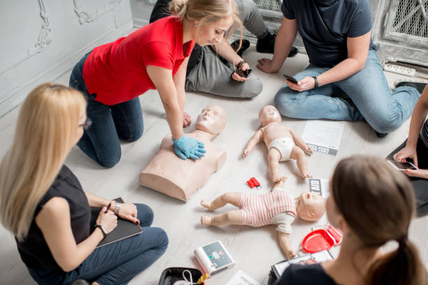 First aid training Young woman instructor showing how to make chest compressions with dummy during the first aid group training indoors cpr stock pictures, royalty-free photos & images