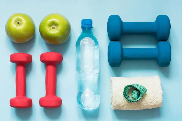 Photo of Sport equipment. Creative flat lay of sport and fitness equipments on blue background with copy space.