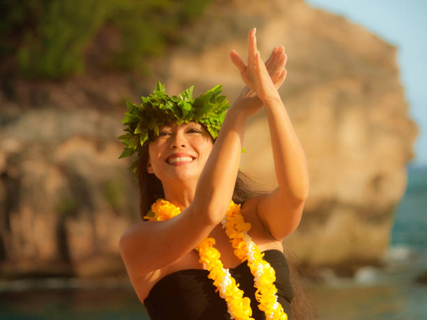 Hawaiian Hula Dancer on the Beach of Kauai A beautiful Hawaiian Hula dancer dancing on the beach of the tropical Hawaiian islands. She is wearing a contemporary Hula dance dress with a lei and flower headdress. Photographed in horizontal format with copy space in Kauai, Hawaii. hula dancer stock pictures, royalty-free photos & images