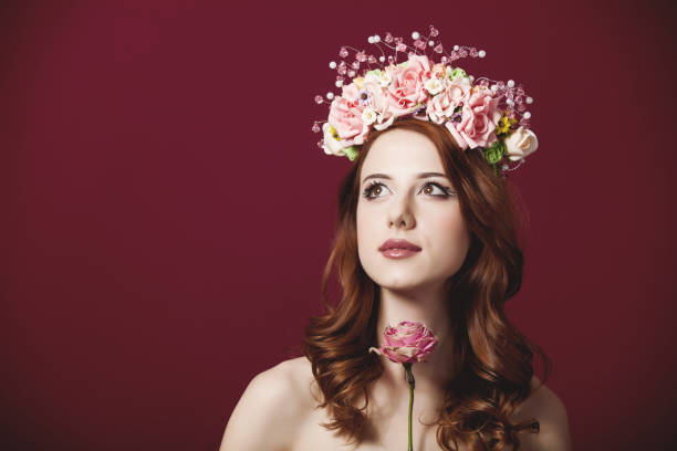 istock Young redhead girl with wreath on red background 929196806