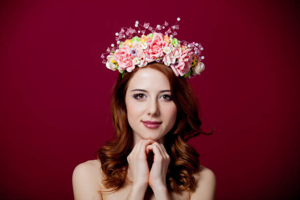 istock Young redhead girl with wreath on red background 929196818