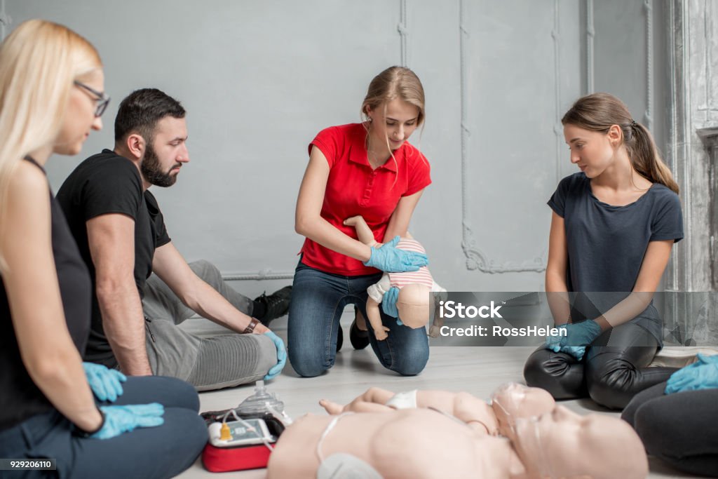 First aid training Instructor showing how to safe a life when the baby is choked sitting during the first aid group training indoors Choking Stock Photo