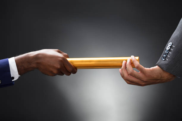 istock Man Passing The Golden Baton To His Partner 929215568