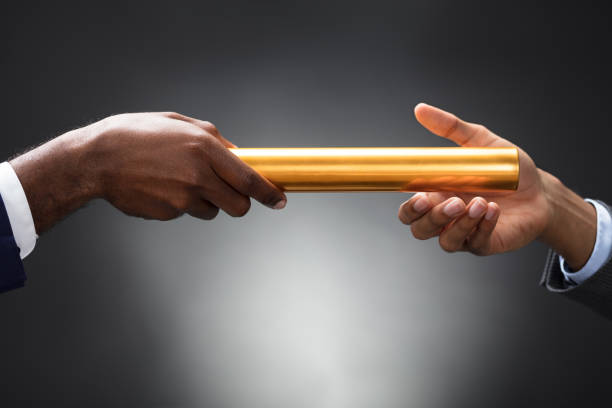 istock Man Passing The Golden Baton To His Partner 929215596