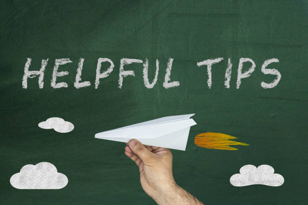 istock Hand holding paper plane and Text Helpful Tips written on green blackboard 929221846