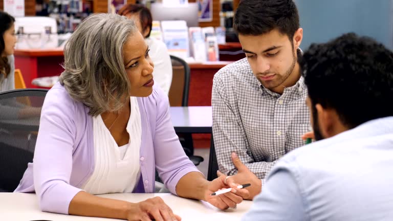 Senior African American female college professor discusses something with male students