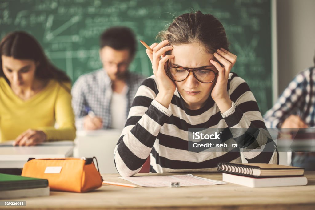 Students solving problem quiz in classroom behind blackboard Student Stock Photo