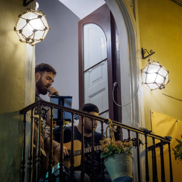 un duo di musicisti di strada che si esibiscono da un balcone sopra una strada nel centro della città di gallipoli (italia). - men editorial musician music foto e immagini stock