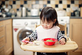 女の赤ちゃんは、家庭の台所でつぶしたアボカドを食べる