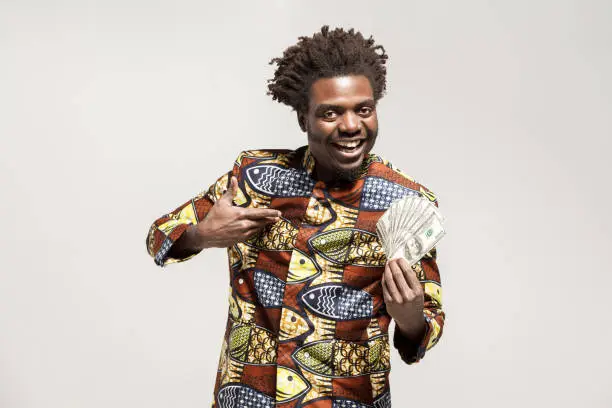 Portrait of african kongo businessman, holding many cash and smile. Indoor, isolated on gray background