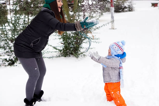 istock Mother and little son having fun in the snow 929269516