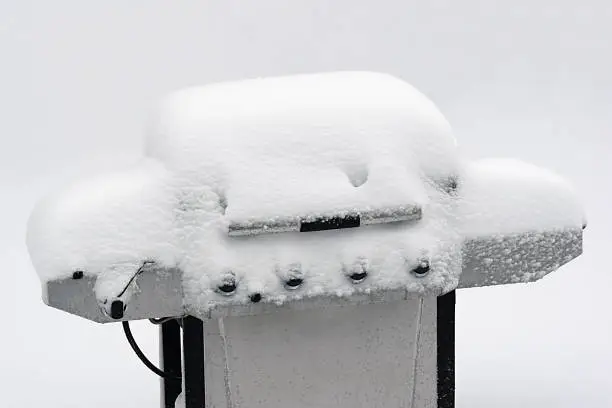 Snow covered outdoor grill during a winter snowstorm frozen cold bar-be-que