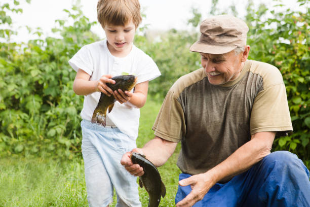 Little Boy and His Grandpa hold the hooked fish