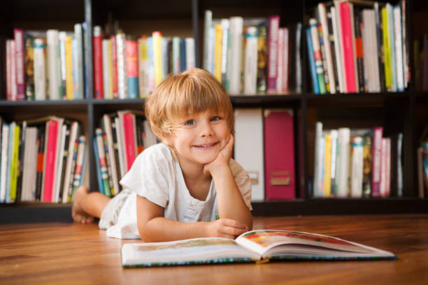 幼児男の子の家で本を読んでいます。本は本棚の近くの小さな男の子 - bookshelf beautiful intelligence learning ストックフォトと画像