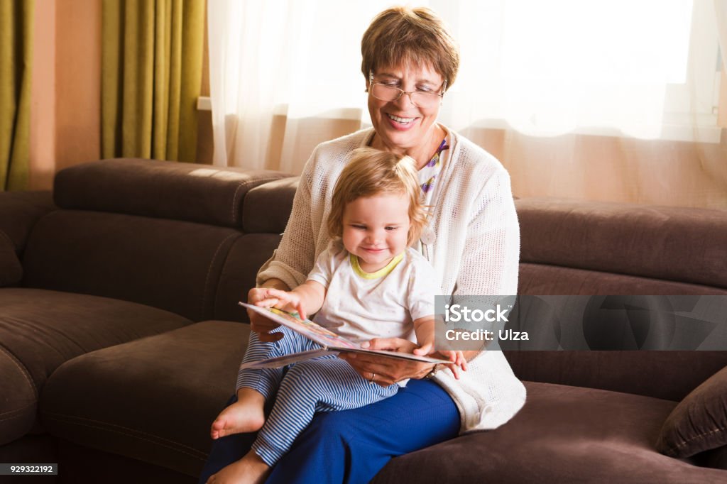 Grandmother reading a tale to her baby granddaughter. Family Reading Leisure Baby - Human Age Stock Photo