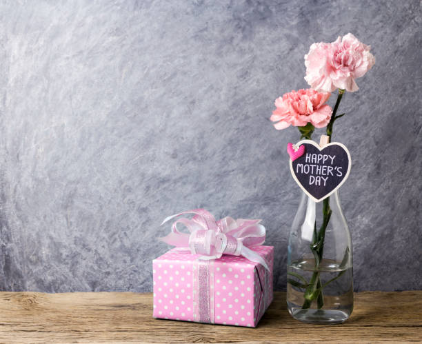 mothers day concept of pink carnation flowers in clear bottle and gift box - flower head bouquet built structure carnation imagens e fotografias de stock