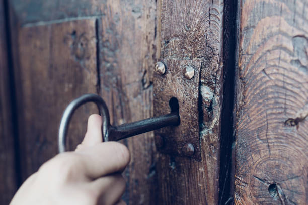 рука проведение металла старинный ключ к разблокировке старой секретной деревянной двери, цвет тон фильма - keyhole lock door antique стоковые фото и изображения