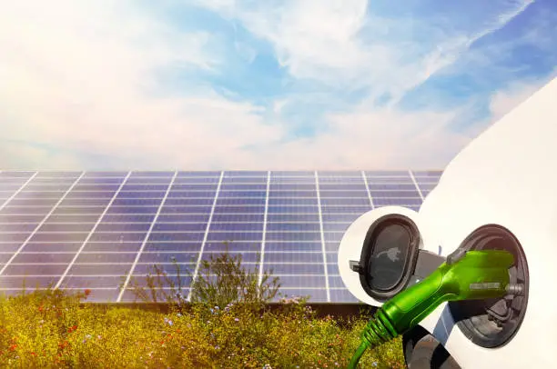 Electric Car charging in nature against solar panels and blue sky
