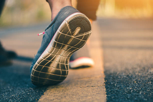 istock Women runner feet on road in workout wellness concept. 929376014