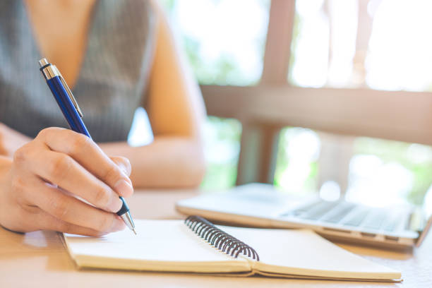 istock Business woman hand is writing on notepad with pen in office. 929428806