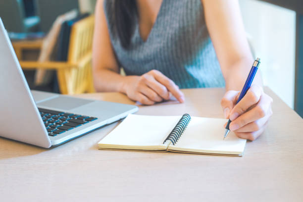 istock Business woman hand is writing on notepad with pen in office. 929428810