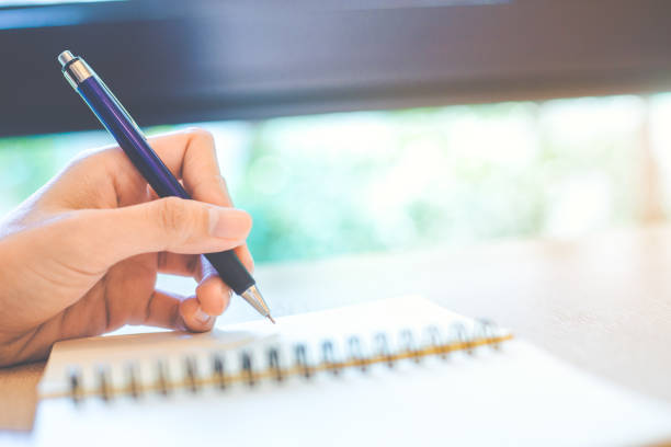 istock Woman hand is writing on a note pad with a pen. 929428814