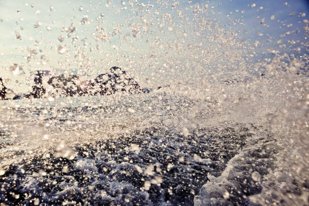 Prop wash spray and wake trails from a high-speed motorboat and island background