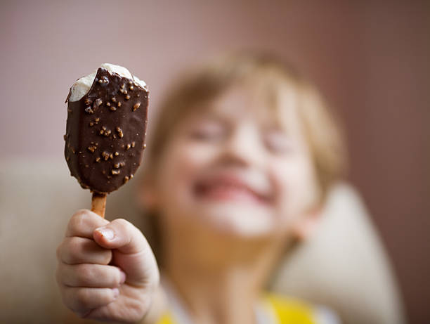 Young boy enjoying a chocolate covered ice cream bar stock photo