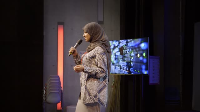 Businesswoman inspirational speaker in hijab talking on conference stage