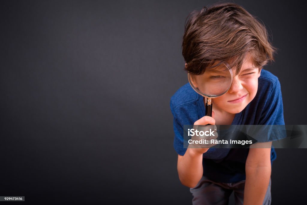 Portrait de garçon mignon à l’aide de la loupe sur fond noir - Photo de Enfant libre de droits