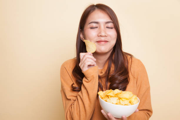 istock Young Asian woman eat potato chips. 929474070
