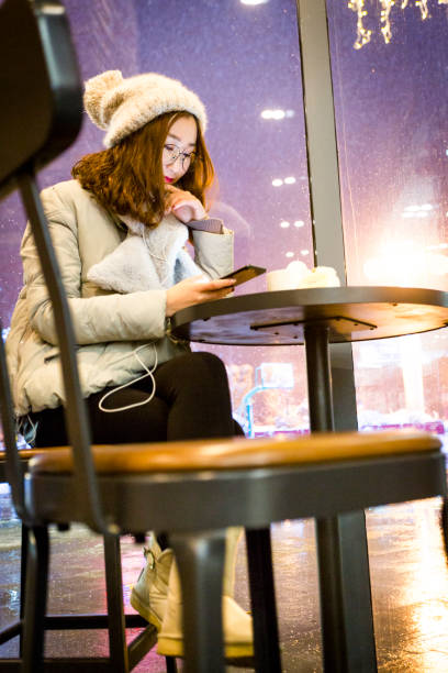 istock pretty woman enjoying coffee time at a snowy night 929480076