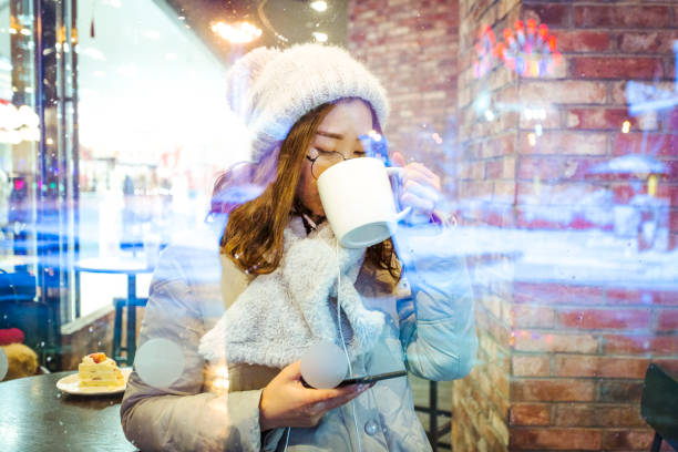 istock pretty woman enjoying coffee time at a snowy night 929482790