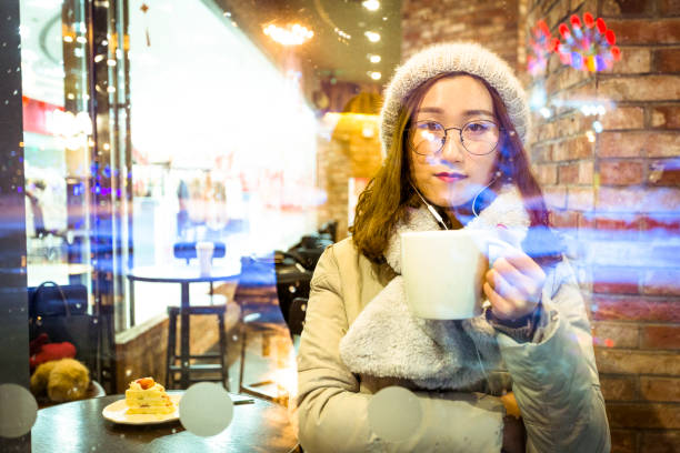 istock pretty woman enjoying coffee time at a snowy night 929482844