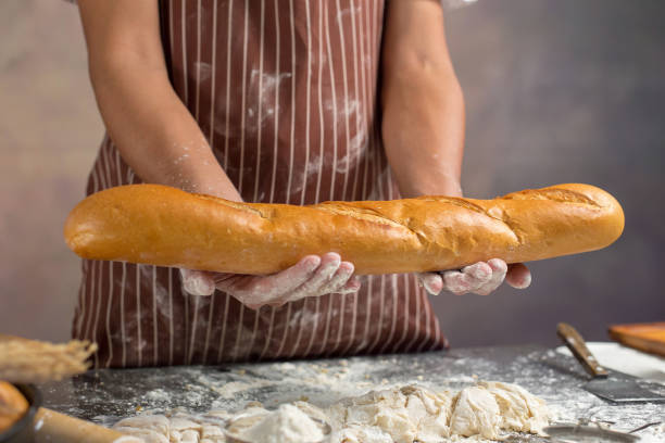 istock Chef holds the fresh bread in hand. Man preparing buns at table in kitchen 929485380