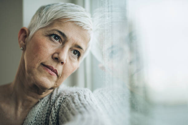 istock Pensive mature woman day dreaming by the window. 929485530