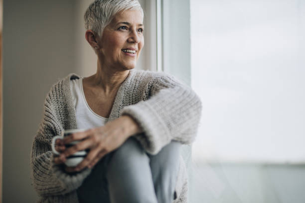 istock Happy mature woman relaxing by the window during coffee time. 929486012