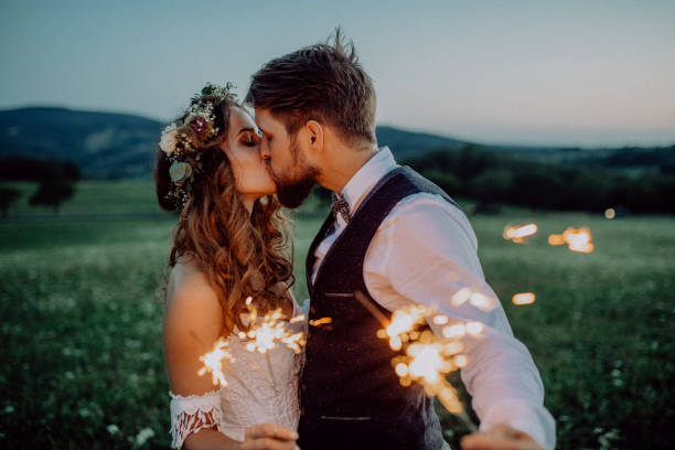 Beautiful bride and groom with sparklers on a meadow. Beautiful young bride and groom on a meadow in the evening, holding sparklers. groom human role photos stock pictures, royalty-free photos & images