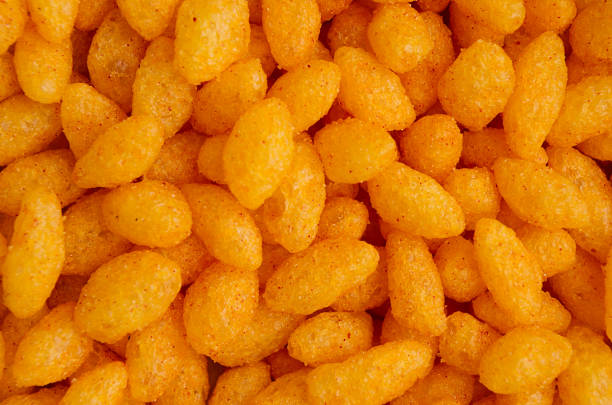 istock Orange spicy corn sticks closeup as background, top view. 929498894