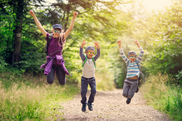 istock Happy kids hikers jumping with joy in forest 929499646