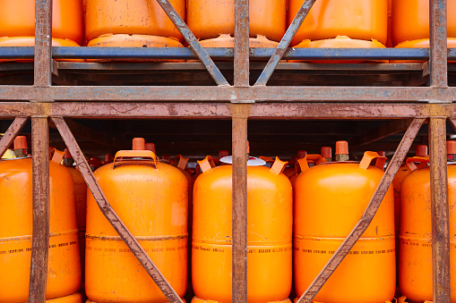 Used gas butane cylinder containers in orange tone. Horizontal