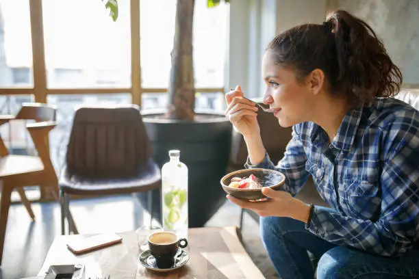 Woman eating cereals with yogurt for breakfast