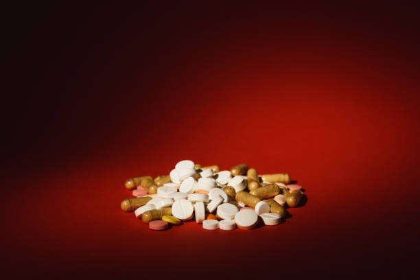 istock Medication white colorful round tablets arranged abstract on dark red color background. Acid acetylsalicylic, capsule pills for design. Health, treatment choice healthy lifestyle concept. Copy space advertisement. 929507094