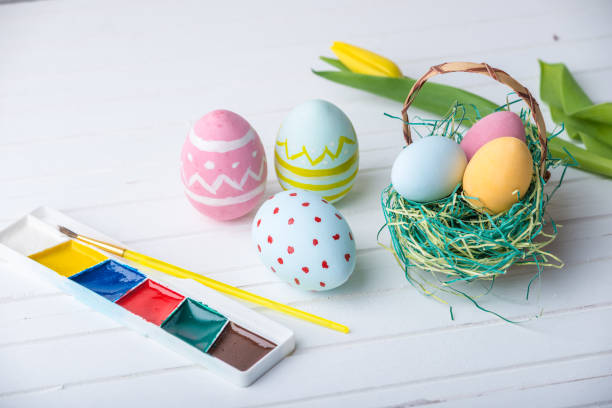 istock Colorful Easter eggs with paints hand painted on a white wooden background. Festive spring card 929548550