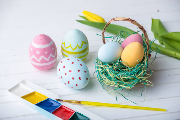 istock Colorful Easter eggs with paints hand painted on a white wooden background. Festive spring card 929548554