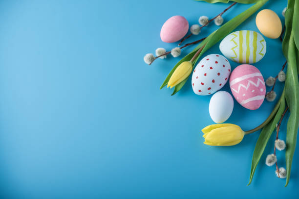 istock Colorful Easter eggs with yellow Tulip hand painted on a blue background. Holiday spring card 929548934