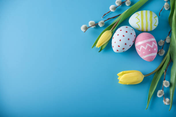 istock Colorful Easter eggs with yellow Tulip hand painted on a blue background. Holiday spring card 929548936
